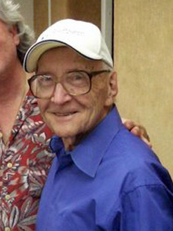 An older man in a blue shirt and white baseball cap.