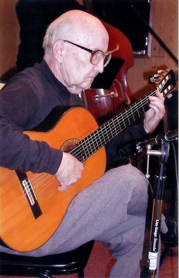 An older man plays a guitar.